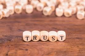 Wooden blocks spelling the word trust on a wooden table background.